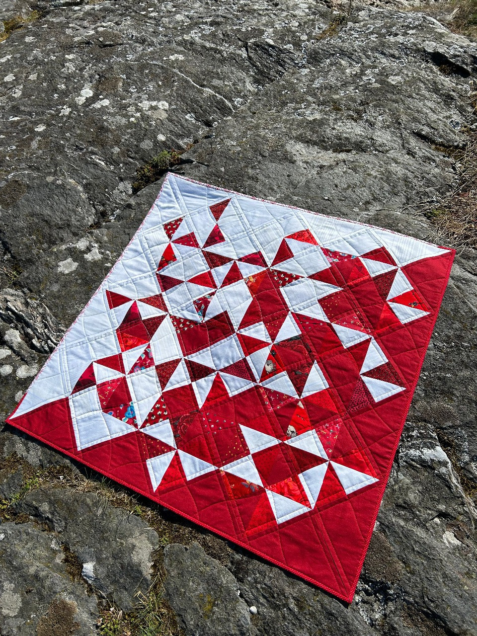Bilde av en rød og hvit quilt sydd av trekanter