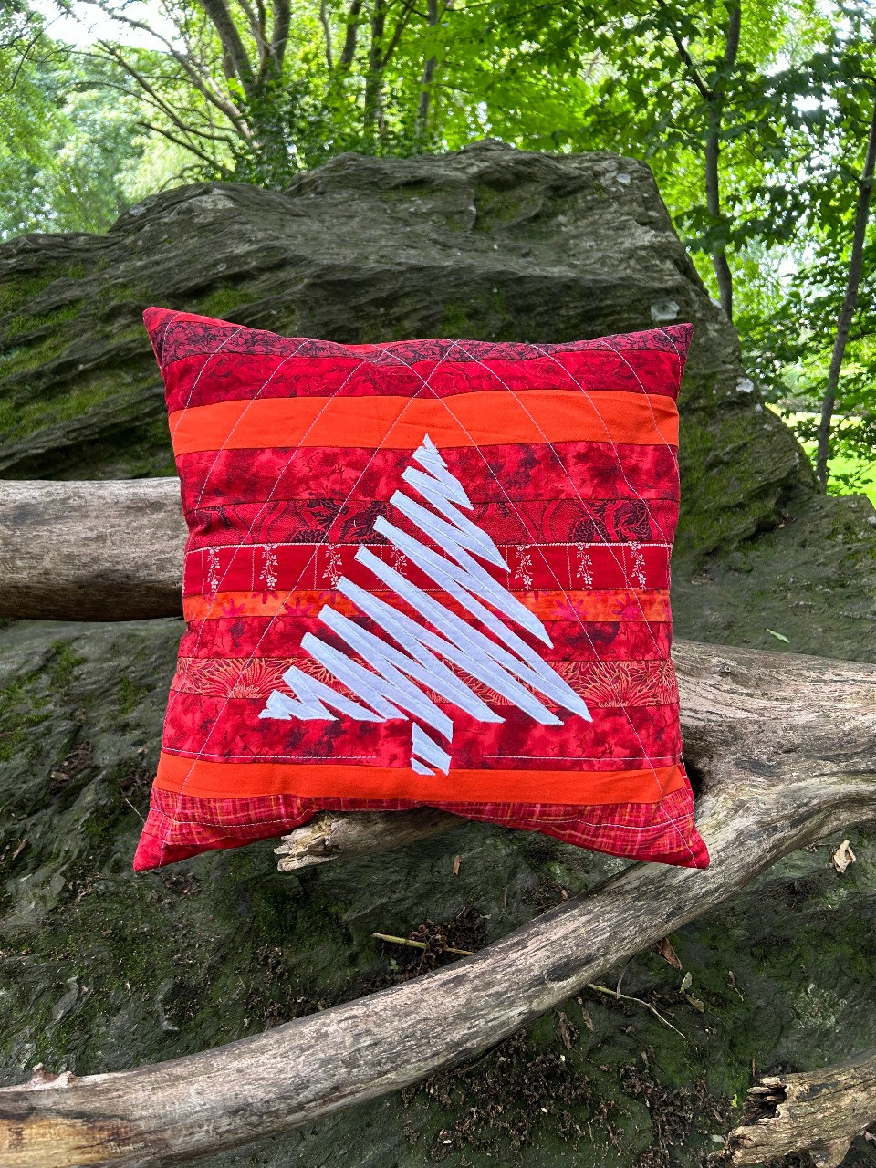 Bild eva en rød og hvit pute. bakgrunnen er sydd av striper, sikksakktreet er applikert på.